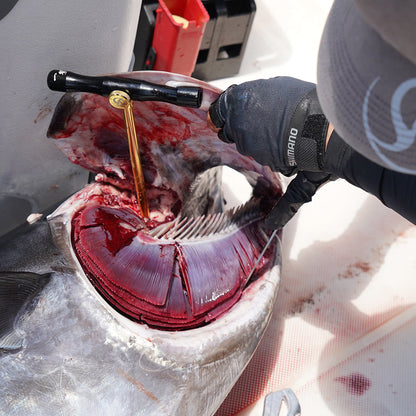Person gutting a fish with a tool on a boat deck