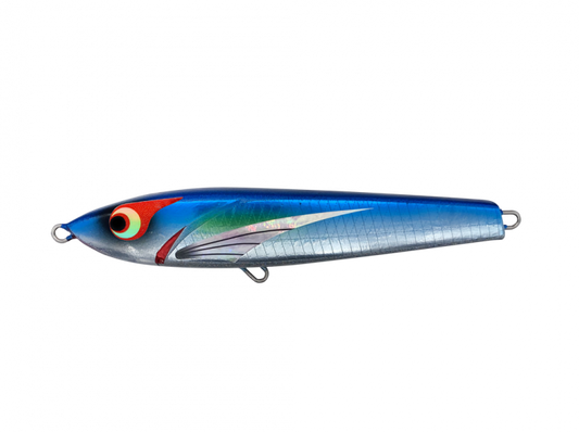 A topwater stickbait lure with a reflective surface and multicolored design, displayed on a table with other fishing lures in the background.